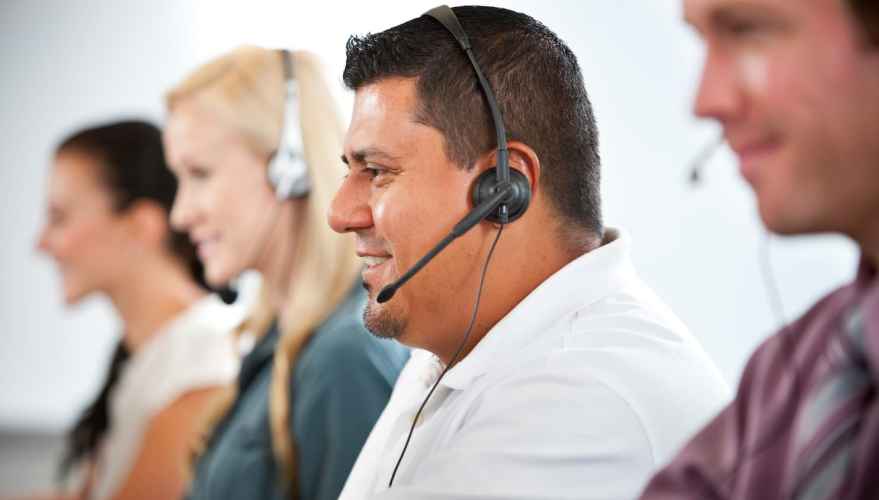 Cuatro personas que llevaban auriculares de operador en un centro de servicio al cliente