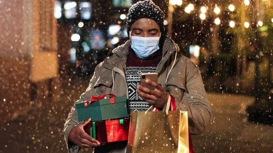Un hombre mira su teléfono mientras hace compras navideñas.
