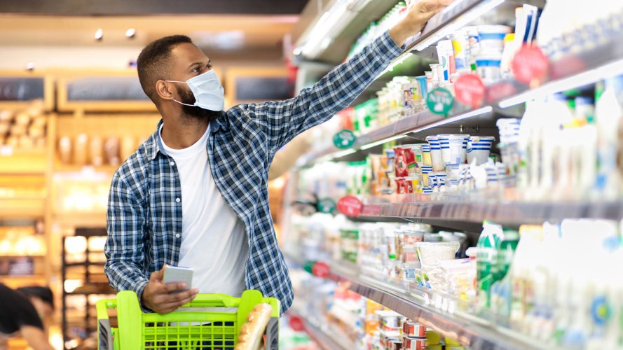 Hombre negro de compras en el supermercado: gestión de promoción comercial
