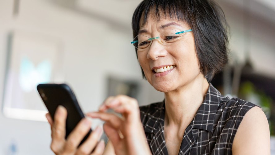 ¿Qué es un chatbot? mujer con gafas sosteniendo e interactuando con su teléfono inteligente